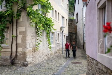 Zwei Personen schlendern durch die Altstadt von Meisenheim am Glan vorbei an schönen alten Häusern.