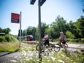 Zwei Personen mit ihren Mountainbikes am Bahnhof Schopp. 