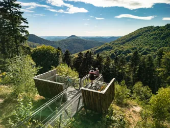 Zwei Personen stehen auf der Aussichtsplattform beim Hermersbergerhof und genießen den Ausblick auf den Pfälzerwald.