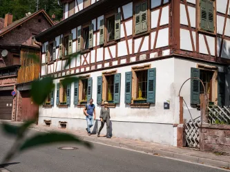 Zwei Personen spazieren entlang eines Fachwerkhauses in Elmstein.