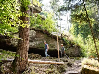 Zwei Personen wandern am Nibelungenfelsen bei Elmstein entlang.