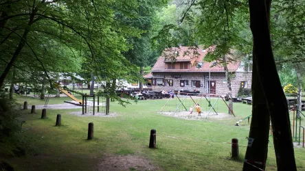 Das Restaurant Starkenbrunnen im Tal des Pfälzerwaldes. Menschen sitzen im Außenbereich und genießen ihr Essen.