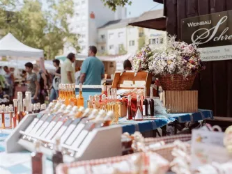Ein Stand auf dem Bauernmarkt in Frankenthal, im Hintergrund weitere Verkaufsstände und zahlreiche Besuchende des Marktes.