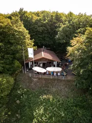 Menschen sitzen im Außenbereich der Hohlsteinhütte und genießen ein Gericht und etwas zu Trinken. 