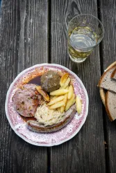 Typische Pfälzer Gerichte und eine Weinschorle auf dem Tisch einer Pfälzerwaldhütte