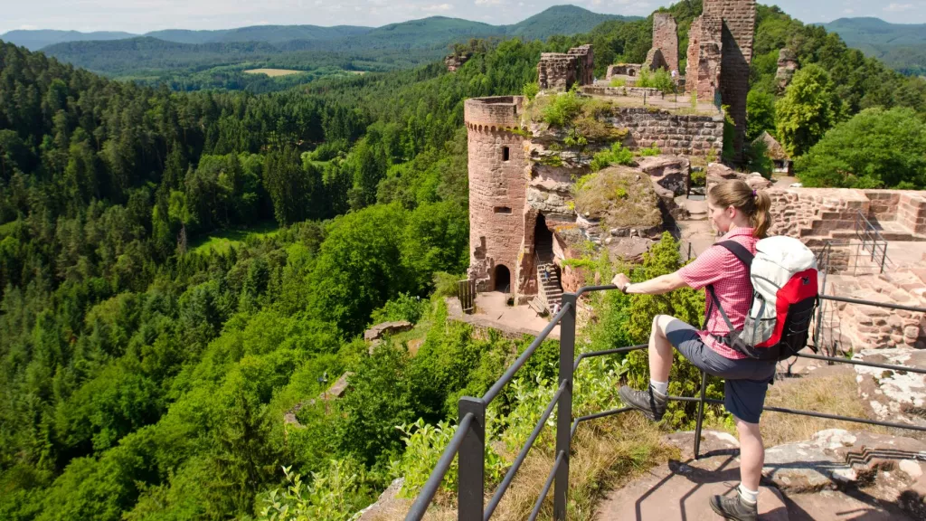 Junge Wandererin mit Ausblick über Pfälzerwald auf Burgruine Alt-Dahn