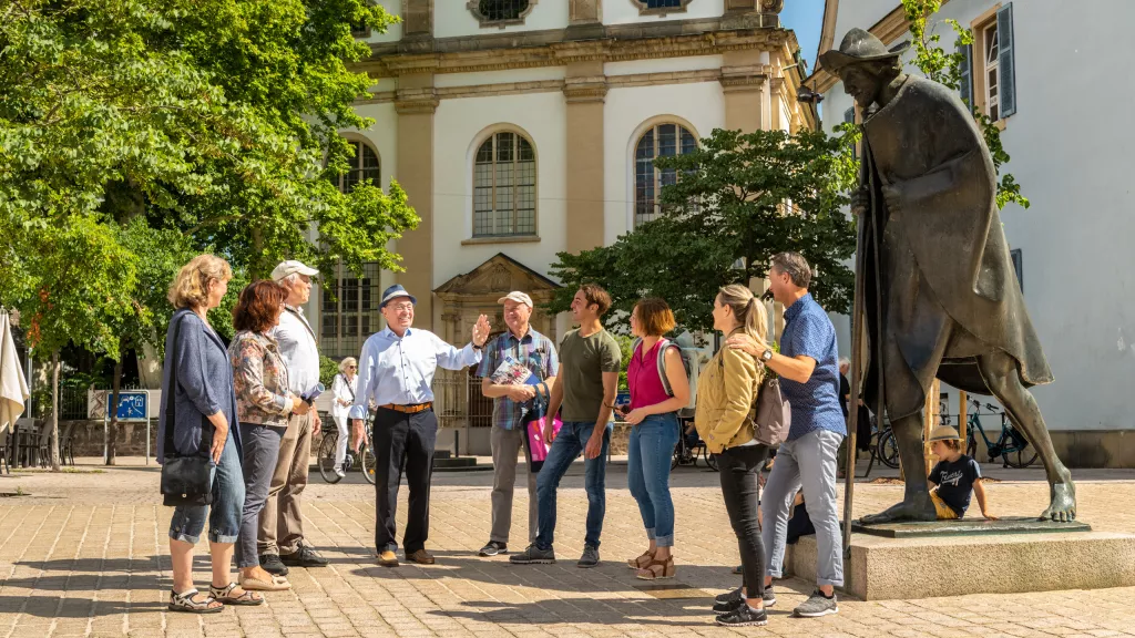 Gruppe von menschen steht bei einer Pilgerstatue in Speyer