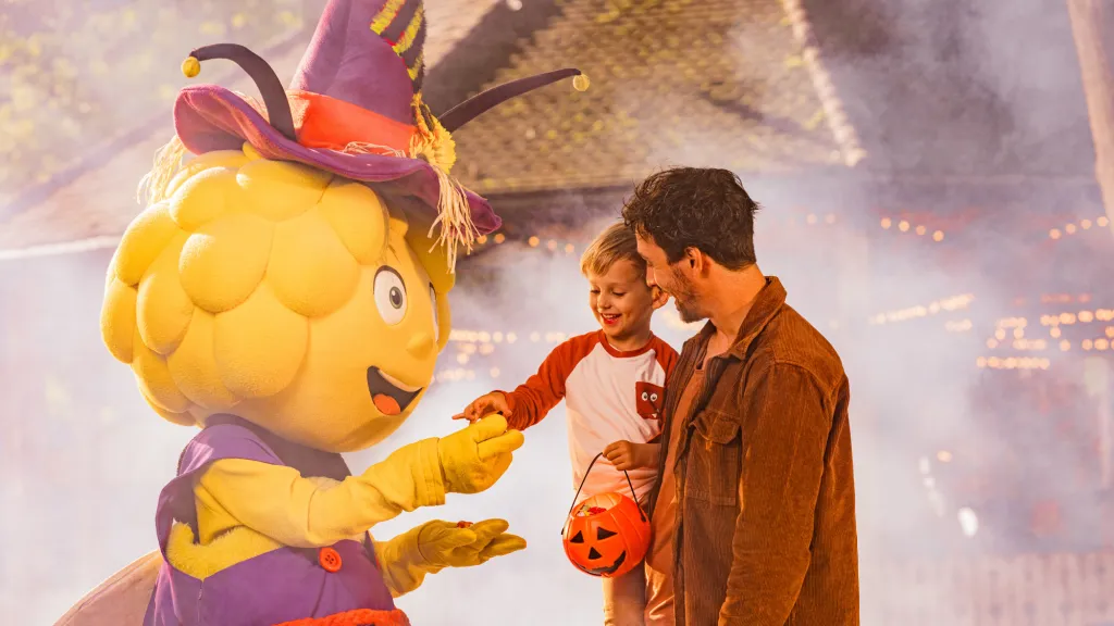 Das Maskottchen der Biene Maia unterhält sich mit Besuchenden des Freizeitparks.