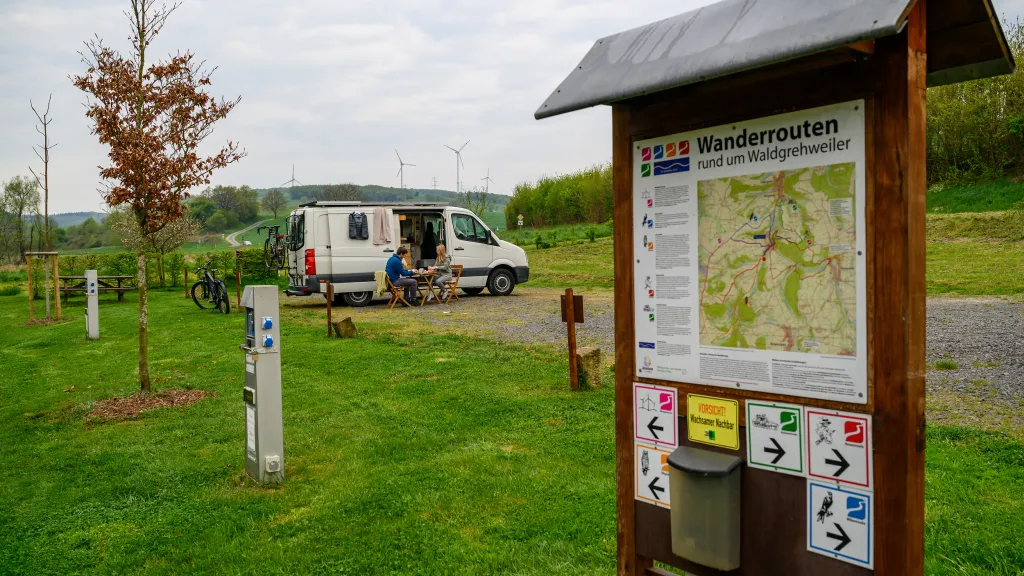 Wohnmobilstellplatz in Waldgrehweiler mit Wohnwagen und Wanderschild