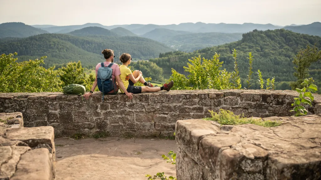 Zwei Personen machen eine Rast auf einer Burg im Pfälzerwald.