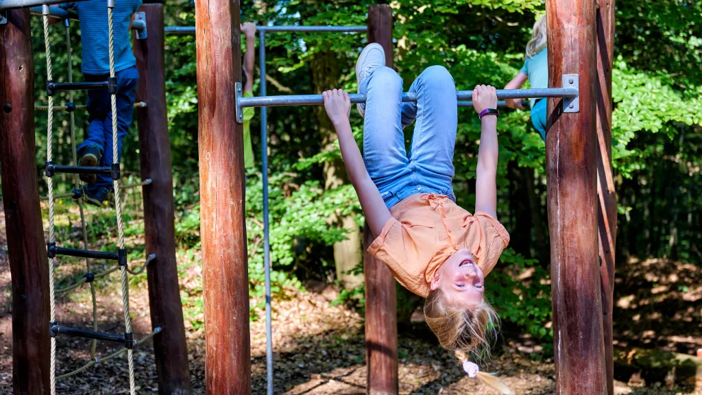 Zwei Kinder spielen auf einem Spielplatz bei einer Pfälzerwald Hütte.