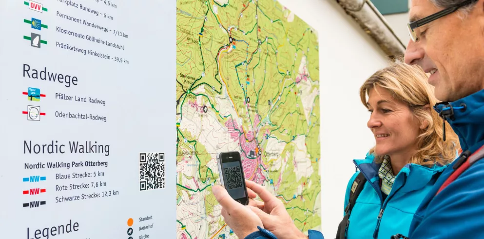 Info-Kartentafel mit Wanderer beim Einscannen des QR-Codes