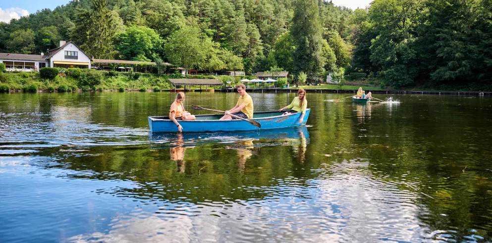 Eine Familie fährt mit einem Ruderboot über einen Weier.