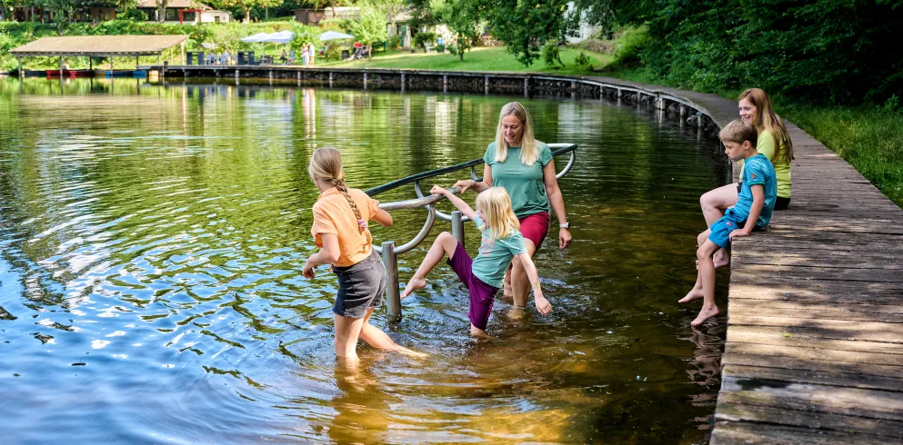 Eine Familie kneippt an einem See