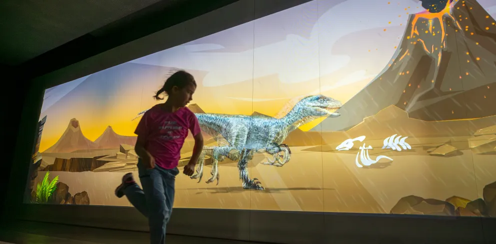 Ein Kind rennt an einem großen Bildschirm - Teil der interaktiven Ausstellung des Dynamikums entlang. 