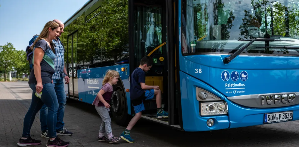 Eine Familie steigt in einen Bus ein.