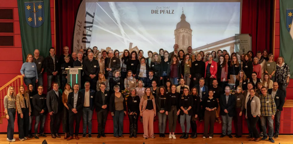 Die Teilnehmenden des 4. Tourismustages Pfalz in Kandel stehen alle vor der Bühne und lächeln in die Kamera