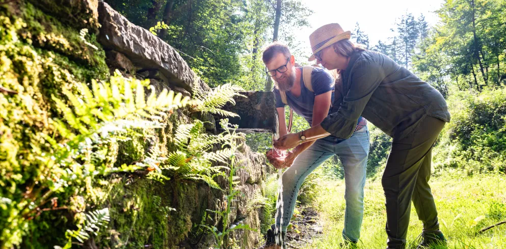 Zwei Personen erfrischen ich an dem fließenden Wasser des Straufelsbrunnen.