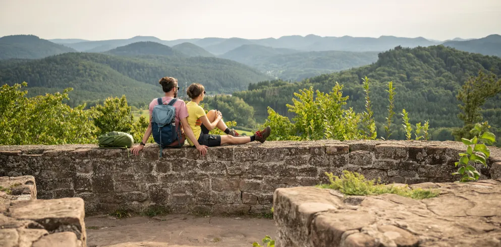 Zwei Personen machen eine Rast auf einer Burg im Pfälzerwald.