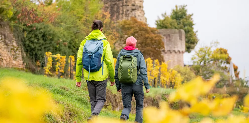 Zwei Personen wandern im Herbst an der Wachtenburg entlang.