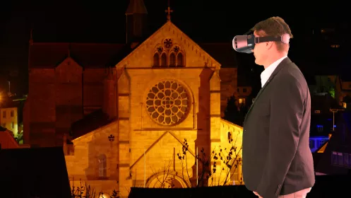 Ein Herr mit VR Brille vor der Abteikirche Otterberg