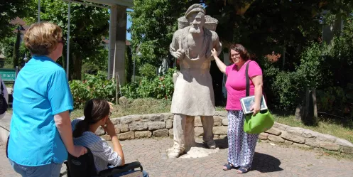 Gästeführerin mit Winzerskulptur aus Stein