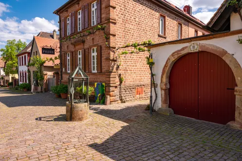 Die Theresienstraße in Rhodt unter Rietburg. Eine Pflastersteinstraße mit alten Fachwerkhäusern.