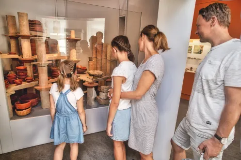 Familie mit zwei Kindern betrachtet Tongefäße in einer Vitrine