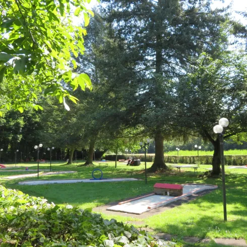 Ein schöner Park mit viel Grün, großen Bäumen und gemütlichen Sitzgelegenheiten. Die Landschaft ist einladend und eignet sich perfekt für einen entspannten Tag im Freien.