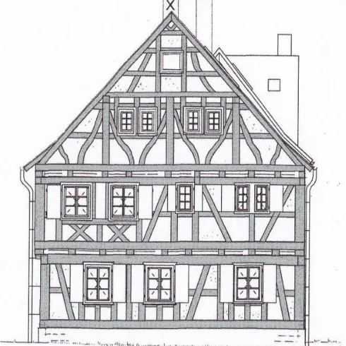 Ein traditionelles Fachwerkhaus mit einem symmetrischen Dach. Die Fassade ist mit Holz- und Putzdetails verziert.