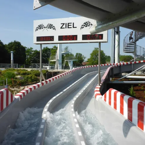 Eine Wasserrutsche mit zwei Fahrbahnen und einem Zielbereich. Der Wasserfluss sorgt für aufregenden Spaß und Abenteuer.
