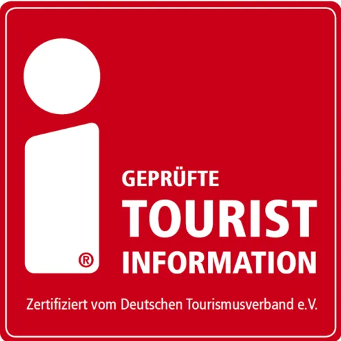 Ein rotes Logo mit einem weißen Informationssymbol. Es zeigt die Worte "Geprüfte Tourist Information" und ist zertifiziert vom Deutschen Tourismusverband e.V.
