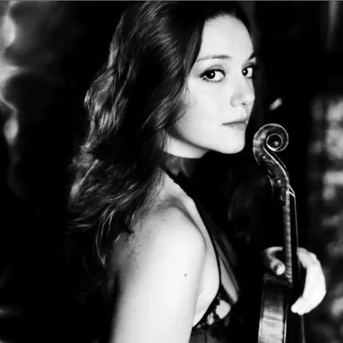 Eine Frau mit langen Haaren hält eine Geige und schaut zur Seite. Das Bild ist in Schwarzweiß gehalten und zeigt eine künstlerische Pose.