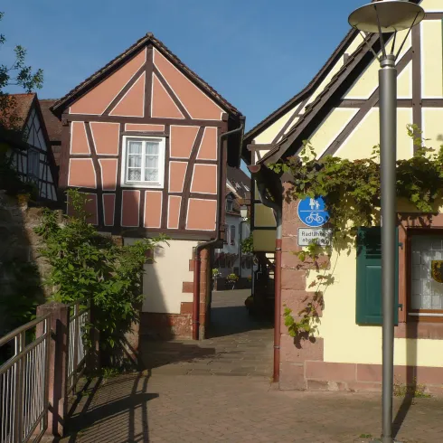 Eine malerische Gasse mit traditionellen Fachwerkhäusern. Die Gebäude sind hell und harmonisch in die Landschaft integriert.
