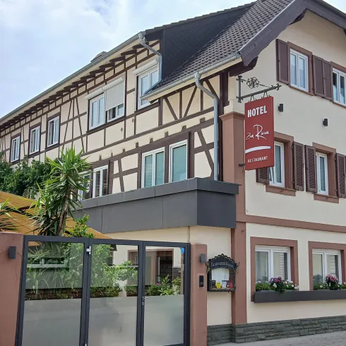 Ein charmantes Hotelgebäude im traditionellen Stil mit Fachwerk. Die Fassade ist freundlich und einladend, umgeben von Pflanzen.