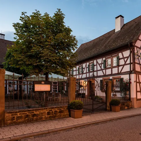 Ein traditionelles Fachwerkhaus mit einem schönen Vorplatz und Bäumen. Die Umgebung ist ruhig und einladend.