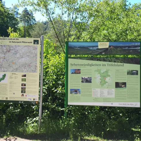 Zwei Informationstafeln im Wald. Die Tafeln zeigen eine Karte und Informationen über die Umgebung.