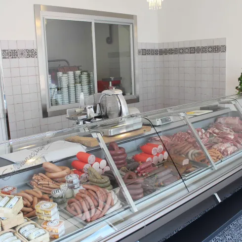 Ein moderner Fleischereibereich mit gläserner Vitrine. Verschiedene Wurst- und Fleischsorten sind in ansprechender Anordnung präsentiert.