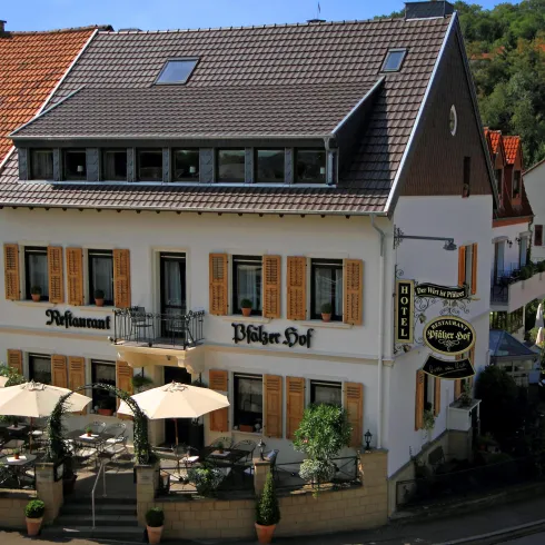 Ein charmantes Restaurant mit einem einladenden Außenbereich und Sonnenschirmen. Das Gebäude hat eine traditionelle Architektur mit Holzläden.
