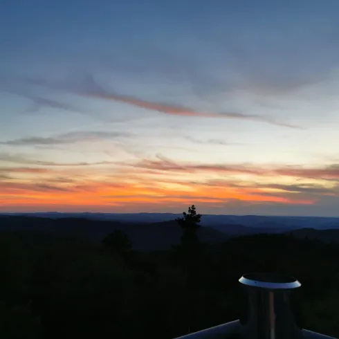 Ein schöner Sonnenuntergang über den Hügeln. Der Himmel ist mit orangefarbenen und lila Wolken gefärbt.