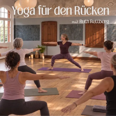 Eine Gruppe von Menschen praktiziert Yoga in einem hellen Raum. Eine Frau leitet die Übung und zeigt eine Pose, während andere Teilnehmer aufmerksam folgen.
