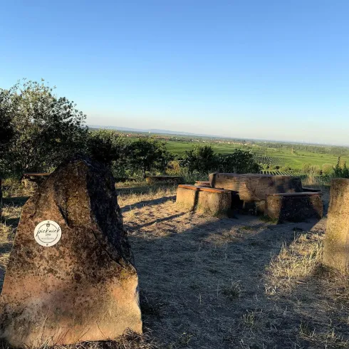 Ein felsiger Aussichtspunkt mit mehreren Steinkreisen und einem weiten Blick auf die grüne Landschaft. Der Himmel ist klar und blau.