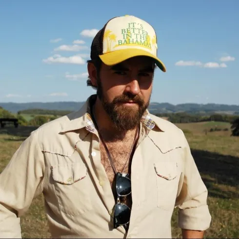Ein Musiker steht im Dunkeln und spielt Gitarre. Ein helles Licht strahlt von hinten und schafft eine stimmungsvolle Atmosphäre.