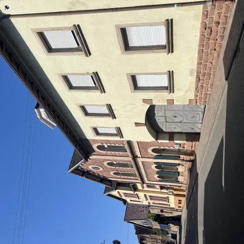 Eine ruhige Straße mit Häusern im modernen und klassischen Stil. Der Himmel ist klar und blau.