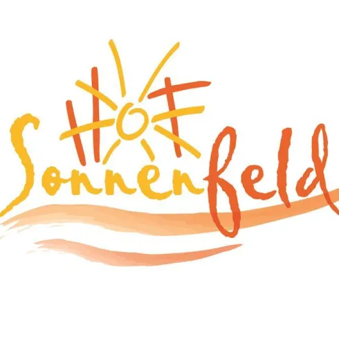 Ein sonniges Logo mit dem Schriftzug „Sonnenfeld“. Die Farben sind warm und einladend.
