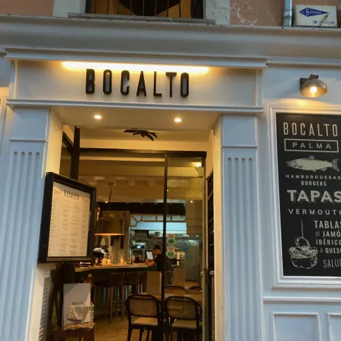 Ein einladendes Restaurant mit dem Namen "Bocalto". Die Vorderseite zeigt eine stilvolle Außenansicht mit Menüs und gemütlichen Sitzgelegenheiten.