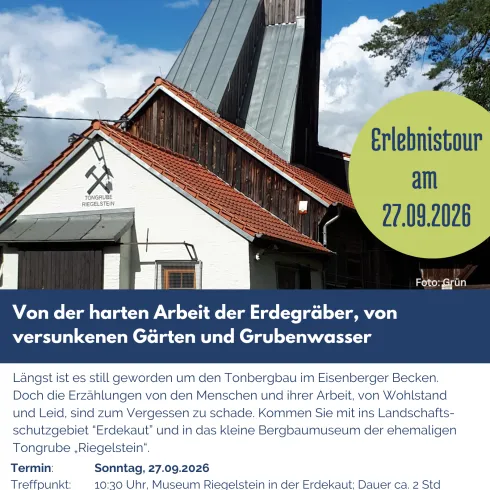 Ein traditionelles Gebäude mit einem markanten Dach sowie einem großen Kirchturm steht vor einem klaren, blauen Himmel. Die Informationstafel weist auf eine Veranstaltung hin, die die Geschichte der Erdarbeiter thematisiert.