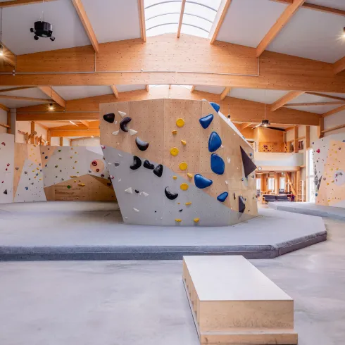 Eine moderne Kletterhalle mit verschiedenen Bouldermöglichkeiten. Die Wände sind mit bunten Griffen zum Klettern ausgestattet.