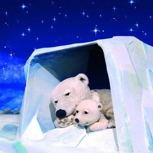 Ein Eisbärenpaar liegt gemütlich in einer Eis-Höhle. Der Nachthimmel ist voller funkelnder Sterne.