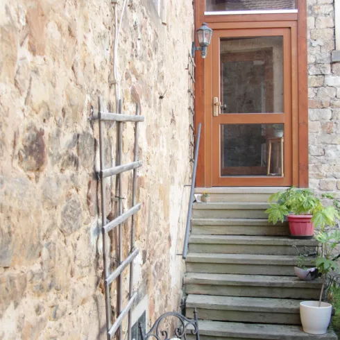 Eine charmante Treppe führt zu einer Holzhaustür. Neben der Treppe steht ein kleiner Tisch mit einer Blumenvase.